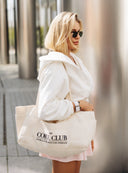 Kobieta niosąca na ramieniu bawełnianą torbę shopper The Core Club Natural w miejskim kadrze