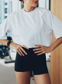 Zbliżenie na biały crop top After Class odsłaniający brzuch oraz czarne szorty