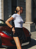 Biały crop top Core z krótkim rękawem ujęty z profilu na miejskim tle
