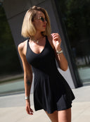 Dopasowana czarna sukienka Court Dress z dekoltem w serek na modelce w plenerze