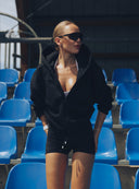 Kobieta na trybunach w czarnej rozpinanej bluzie Hoodie Club Black i spodenkach