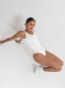 Siedząca modelka w dopasowanym kremowym body Zarina Ecru oparta o ścianę