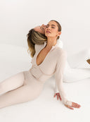 Siedząca na podłodze modelka w beżowym prążkowanym kombinezonie Meryl