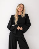 Modelka w czarnym longsleeve Suri ze ściągniętymi rękawami i ciemnych spodniach