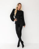 Sylwetka w czarnym longsleeve Suri zestawionym z legginsami i obcasami
