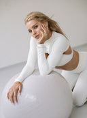 Kremowe bolerko treningowe Comfy Vanilla narzucone na top w stylizacji z piłką fitness
