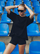 Kobieta w czarnym t - shircie Sunday Tee i ciemnych spodenkach na trybunach