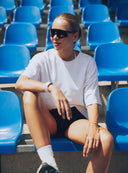 Modelka na niebieskich krzesełkach w luźnym białym t - shircie Sunday Tee