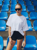 Stojąca modelka w białym t - shircie Sunday Tee i czarnych szortach