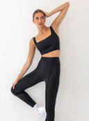 Modelka w dynamicznym ruchu prezentuje czarny krótki top Miriam i legginsy z wysokim stanem